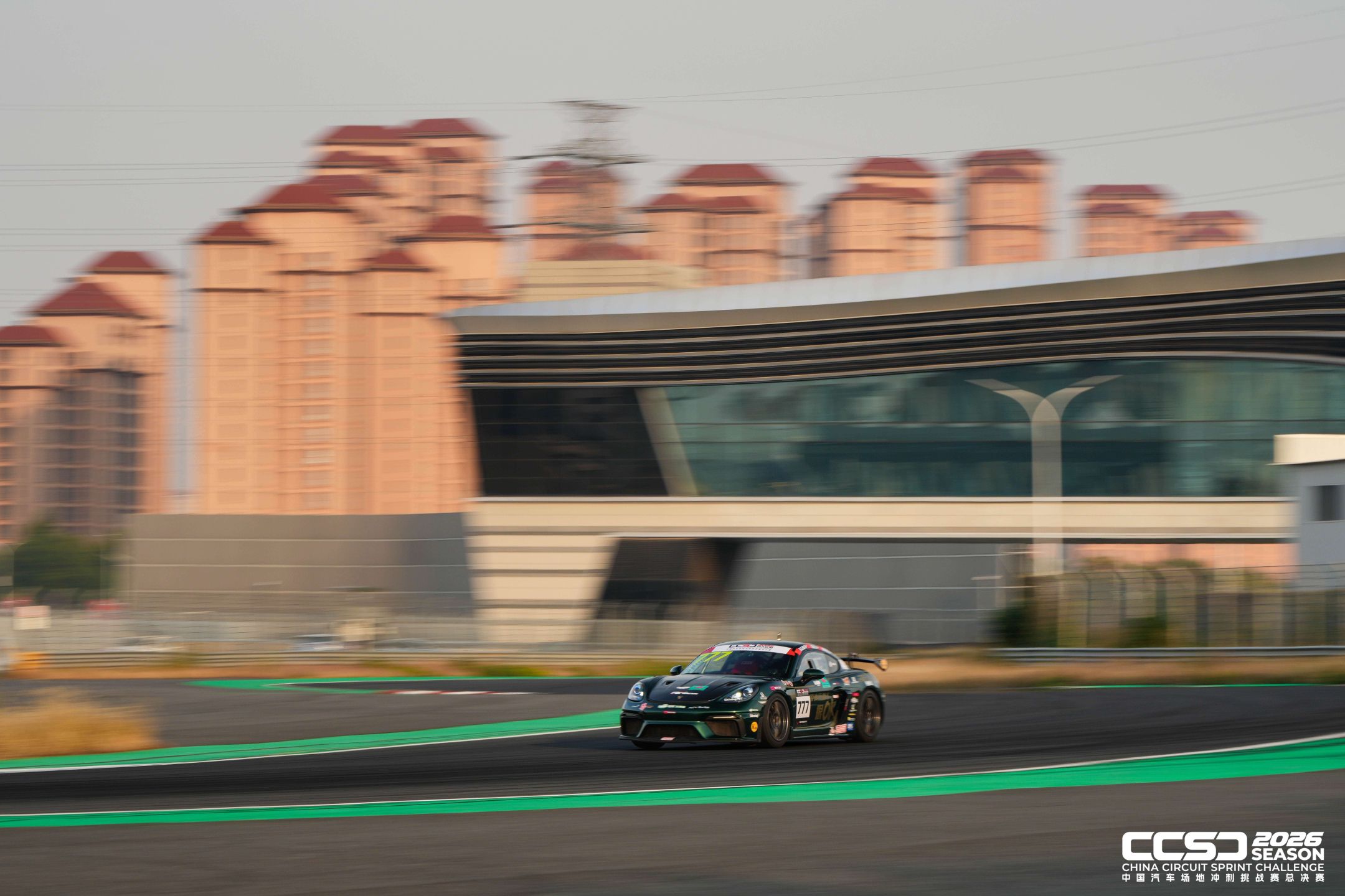 Racing car passing buildings beside a circuit